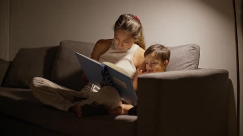 Woman Reads to Child on Couch at Night