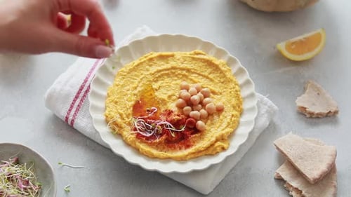 Hummus Being Topped with Sprouts in Overhead Shot