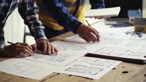 Architects Reviewing Blueprints and Taking Notes at Workplace