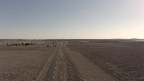 Lone Car Drives Through Sparse Rural Landscape