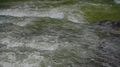 Fresh water stream with ripples due to the rocky bottom. Water stream on the rocky river - Slow moti