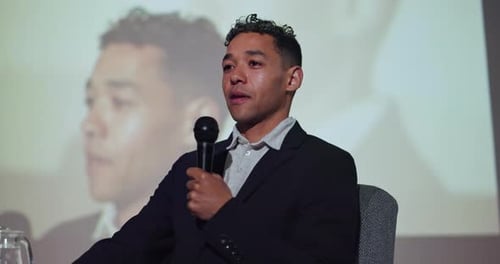 Young Adult Speaking Into Microphone During Presentation