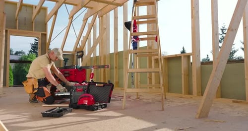 Construction Worker Assembles Tools While Building a Wooden Frame in a New Home During Daylight