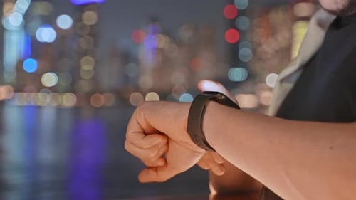 Man Citizen Using Smartwatch Touching Screen at Night on Waterfront in City
