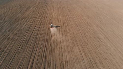 Farming Tractor Moving on Agricultural Field for Plowing Land Before Seedins Crops