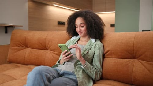 Woman Relaxing on Sofa Using Mobile Phone