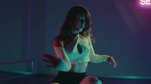 Young Woman Dancing with Athleticism and Grace in a NeonLit Studio