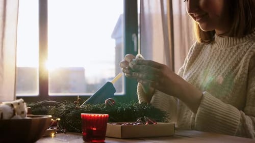 Woman Crafting Christmas Wreath at Sunny Wooden Table