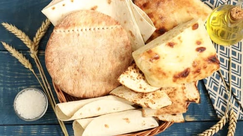 Délicieux pain pita et lavash dans un panier en osier tournant sur une table en bois bleue, posé à plat