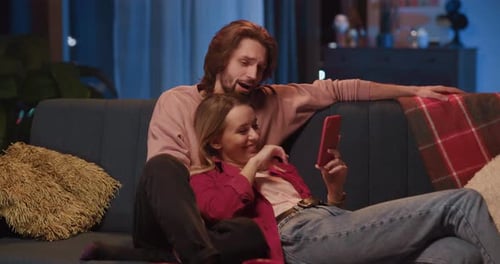 Couple Relaxing on Couch with Smartphone at Night