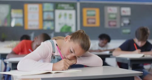 In school, girl smiling and sitting at desk with open book in classroom