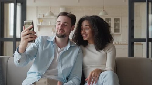 Smiling Couple Video Chats Together on Couch