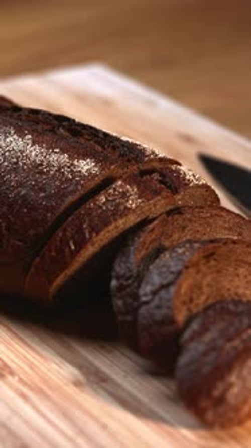 Sliced Dark Rye Bread Loaf on a Wooden Cutting Board Media