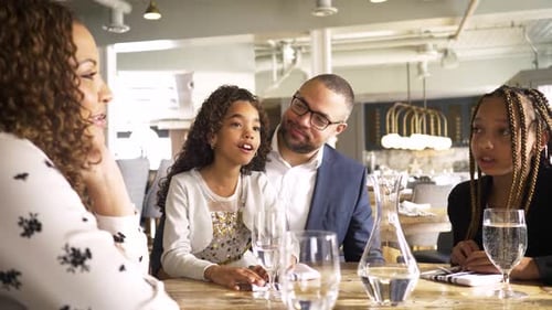 Family Together at Restaurant Table Conversing and Smiling