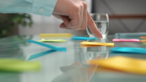 Hands Organizing Colorful Sticky Notes on Table Surface