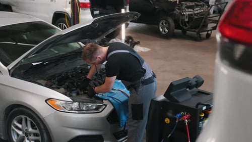 Auto mechanic working on car engine in mechanics garage. Repair service