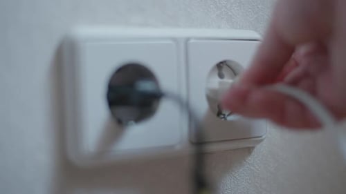 Plugging White Electrical Cord into Wall Socket