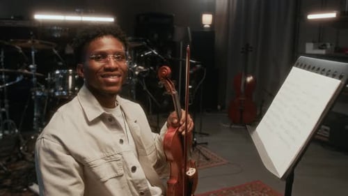 Smiling Black Man Holding Violin in Music Studio