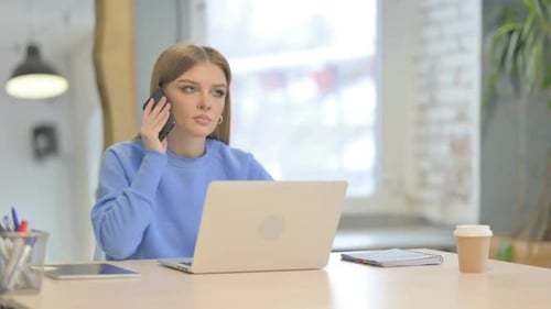 Woman Works at Laptop and Answers Phone