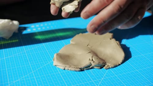 Hands Shaping Clay Material on Table