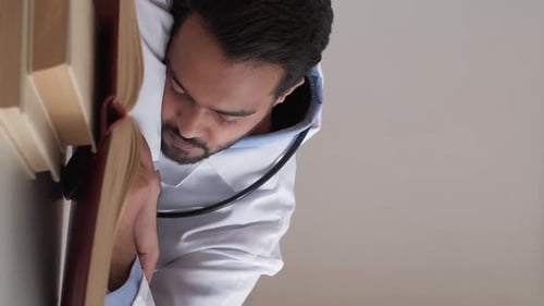 Man in White Coat Sleeping Next to Books