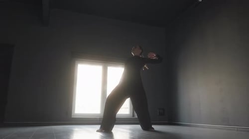 Graceful Woman in Black Dances Contemporary in Dark Studio with Bright Window