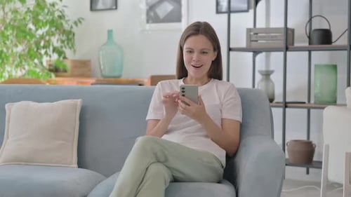 Young Woman Celebrating Success on Mobile Phone