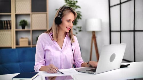 Woman Working at Desk with Laptop and Headset