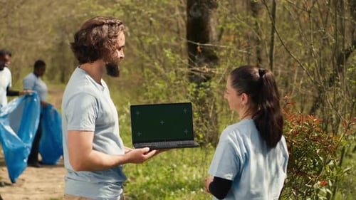 Team of Climate and Nature Activists Using Laptop with Greenscreen Near a Forest