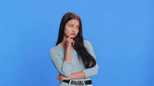 Young Woman Thinking Against Blue Background
