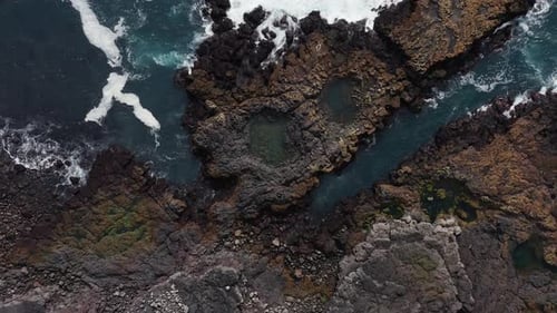 Basalt rock coast in Iceland with tranquil waves hitting shore, aerial
