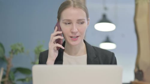 Close Up of Businesswoman Talking on Phone while using Laptop