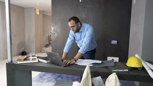 Man working on laptop in construction site office