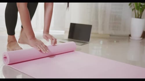 Woman Rolling Pink Yoga Mat Before or After Sport Preparation Working Out