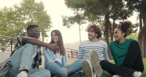 Group of Diverse College Student Friends Laughing and Chatting Sitting on the Grass on Campus