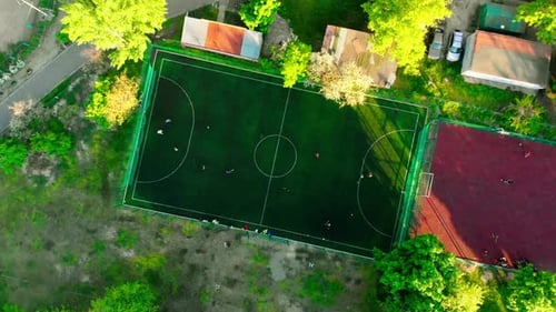 Small Football Field on the Street in the City at Sunset with Players