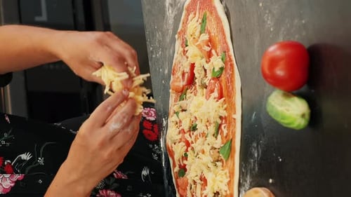 Scattering grated cheese over pizza