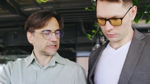 Two Men Discussing Business on Laptop in Office