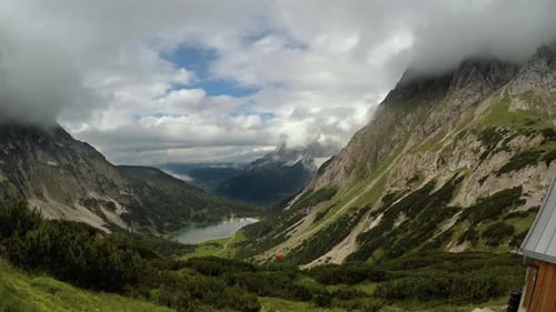 A dramatic time-lapse look from Coburger Hütte down a valley, across a clear mountain lake towards t