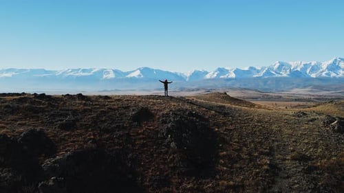 Hiker Stands Triumphantly on a Mountain Ridge Against a Clear Blue Sky
