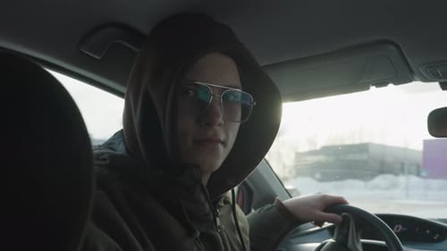Young Adult inside Vehicle Wearing Hood and Glasses