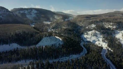 Aerial view of winding mountain highway going through snowy mountain pass
