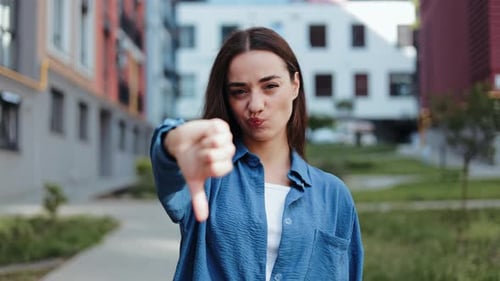 Young Adult Woman Gives Thumbs Down Gesture Outside