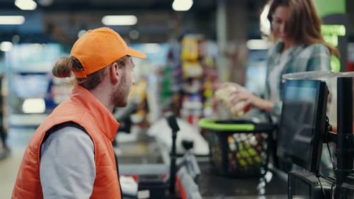 Caucasian Young Adult Cashier Scanning Organic Food Items Products on Cashier Line Serving the