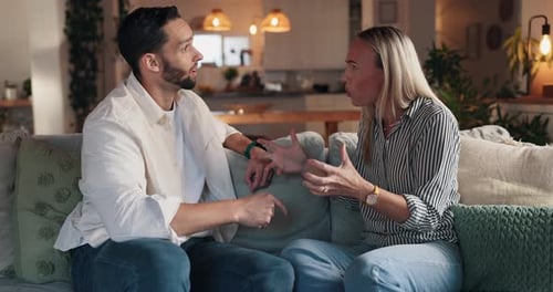 Couple Engaged in Serious Discussion on Couch Indoors