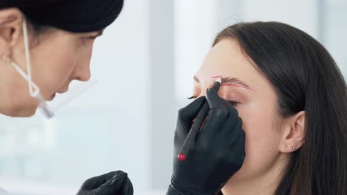 Cosmetician Marking Eyebrows on Young Adult Woman
