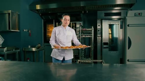 Baker with fresh pastries in professional kitchen