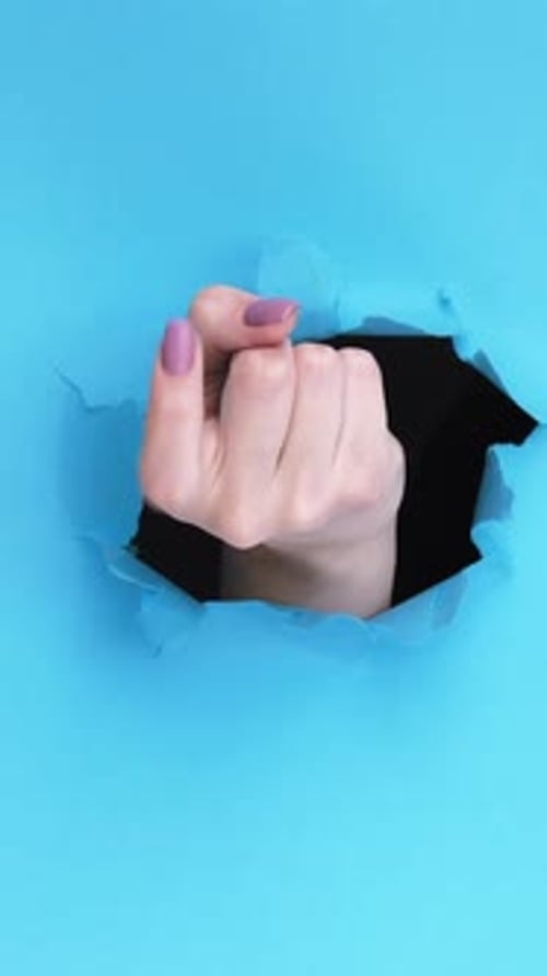Hand Through Torn Blue Paper Background