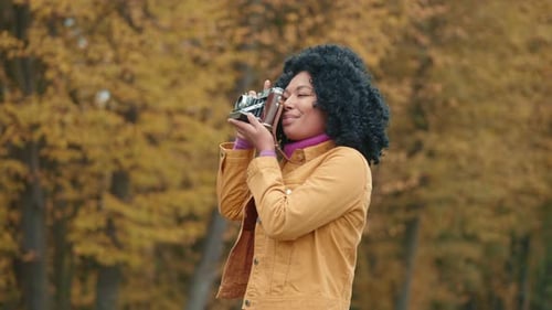 Medium Shot of Colored Woman with Vintage Camera Taking Pictures of Autumn Park