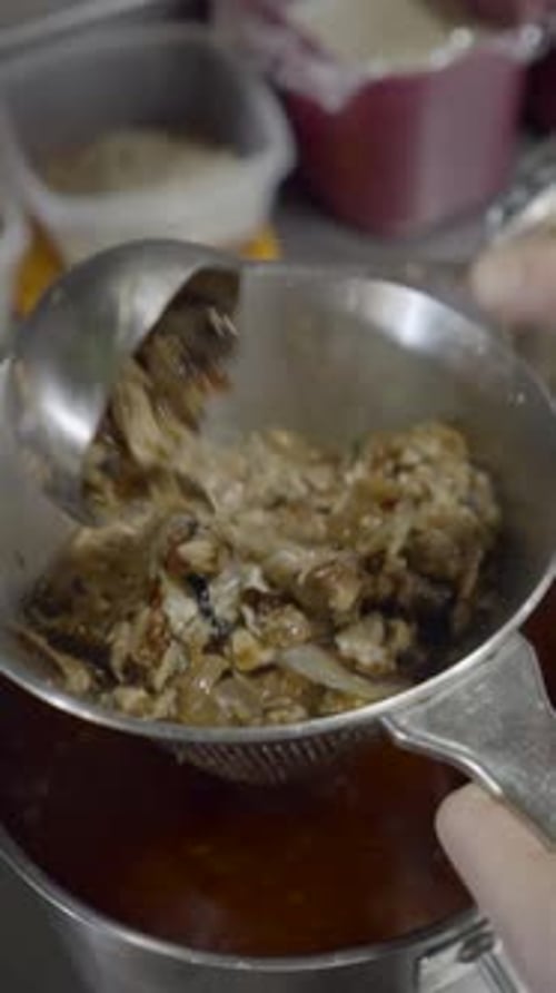 Close View of Male Chef’s Hands Straining Sauce Into Pot in Kitchen